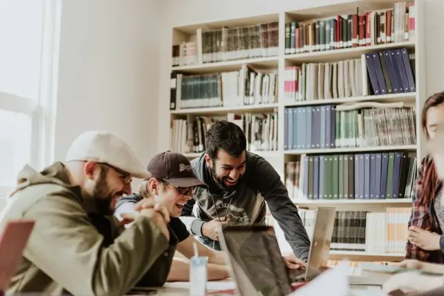 Students working together around a laptop in a library