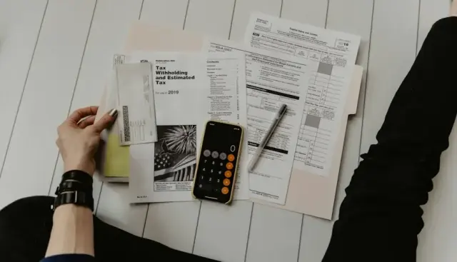 Hands reviewing financial documents with a calculator