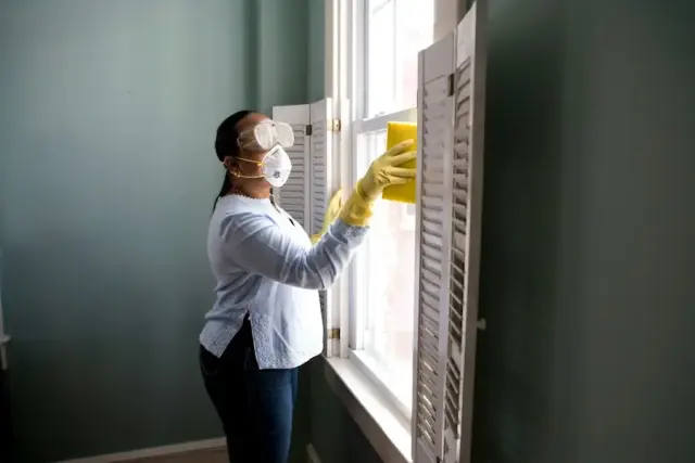 Cleaner in protective gear cleaning a window