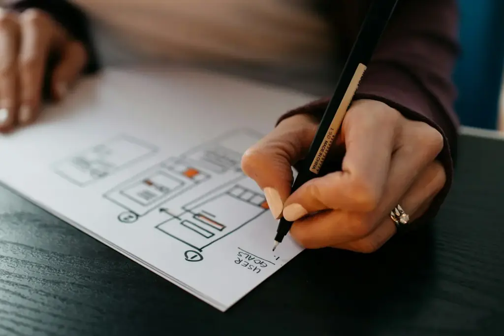 Hand drawing a website wireframe with a pen on paper